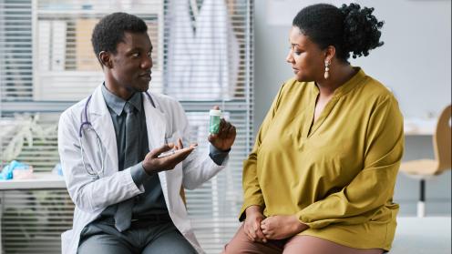 African American doctor holding medications talking to overweight african american woman
