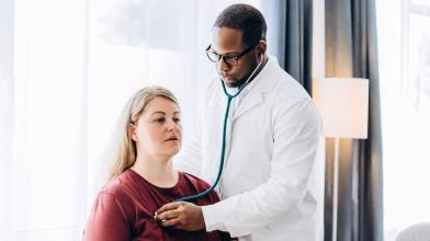 Doctor checking patient's heart with stethoscope