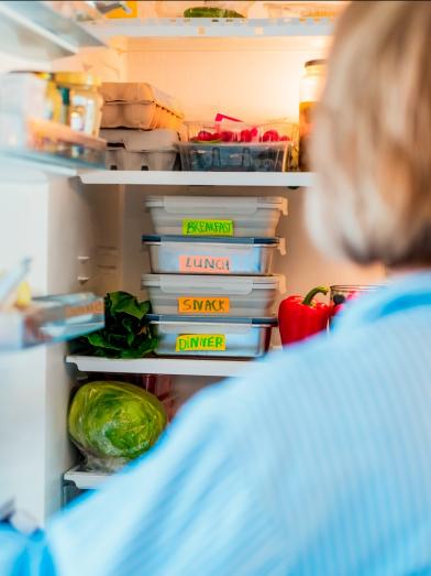 An over-the-shoulder shot looking into a fridge with meal planning tubs