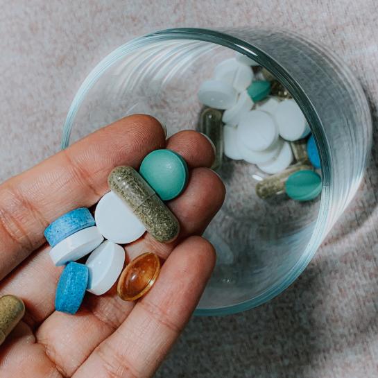 Person puttting pills and tablets in a glass cup
