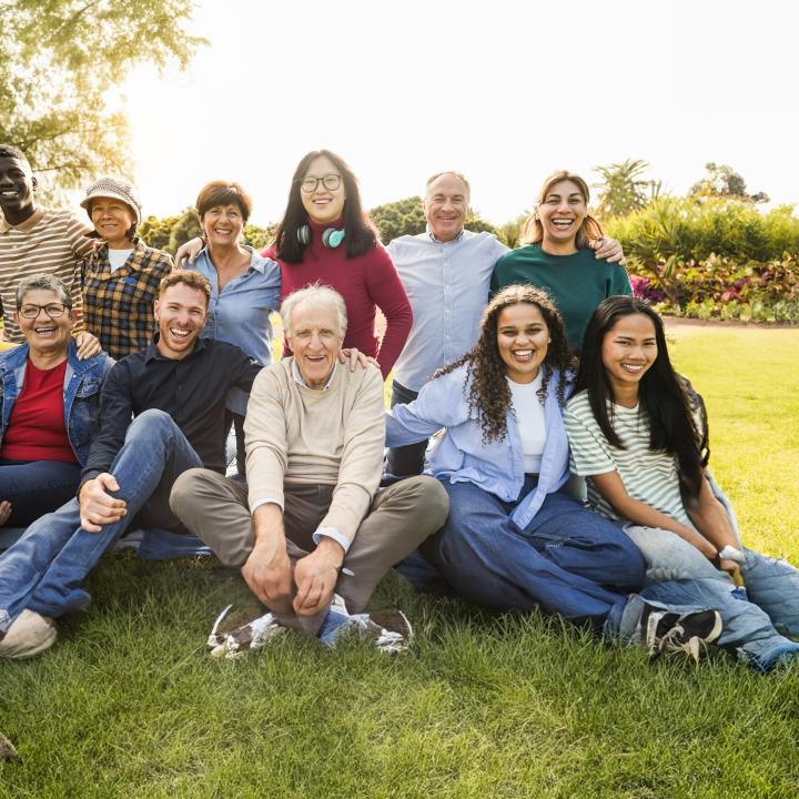Group of multigenerational people smiling on lawn outside on sunny day