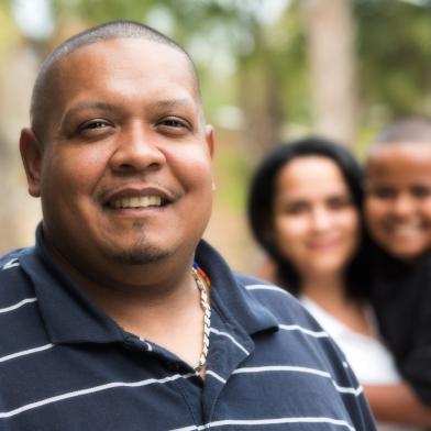 Smiling African American heavy-set man with wife and child in background