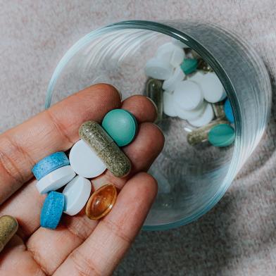 Person puttting pills and tablets in a glass cup