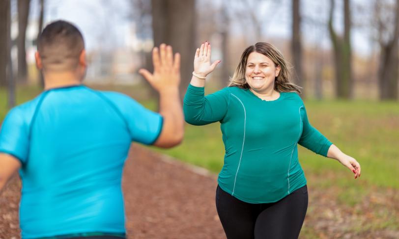 Overweight husband and wife giving high five during outside exercise