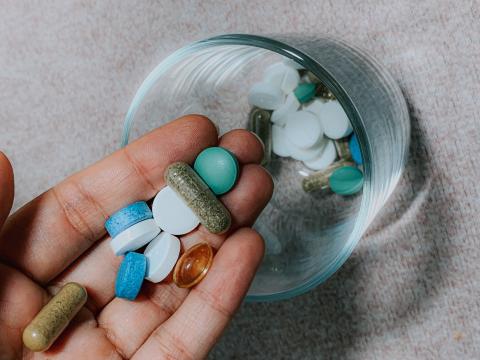Person puttting pills and tablets in a glass cup